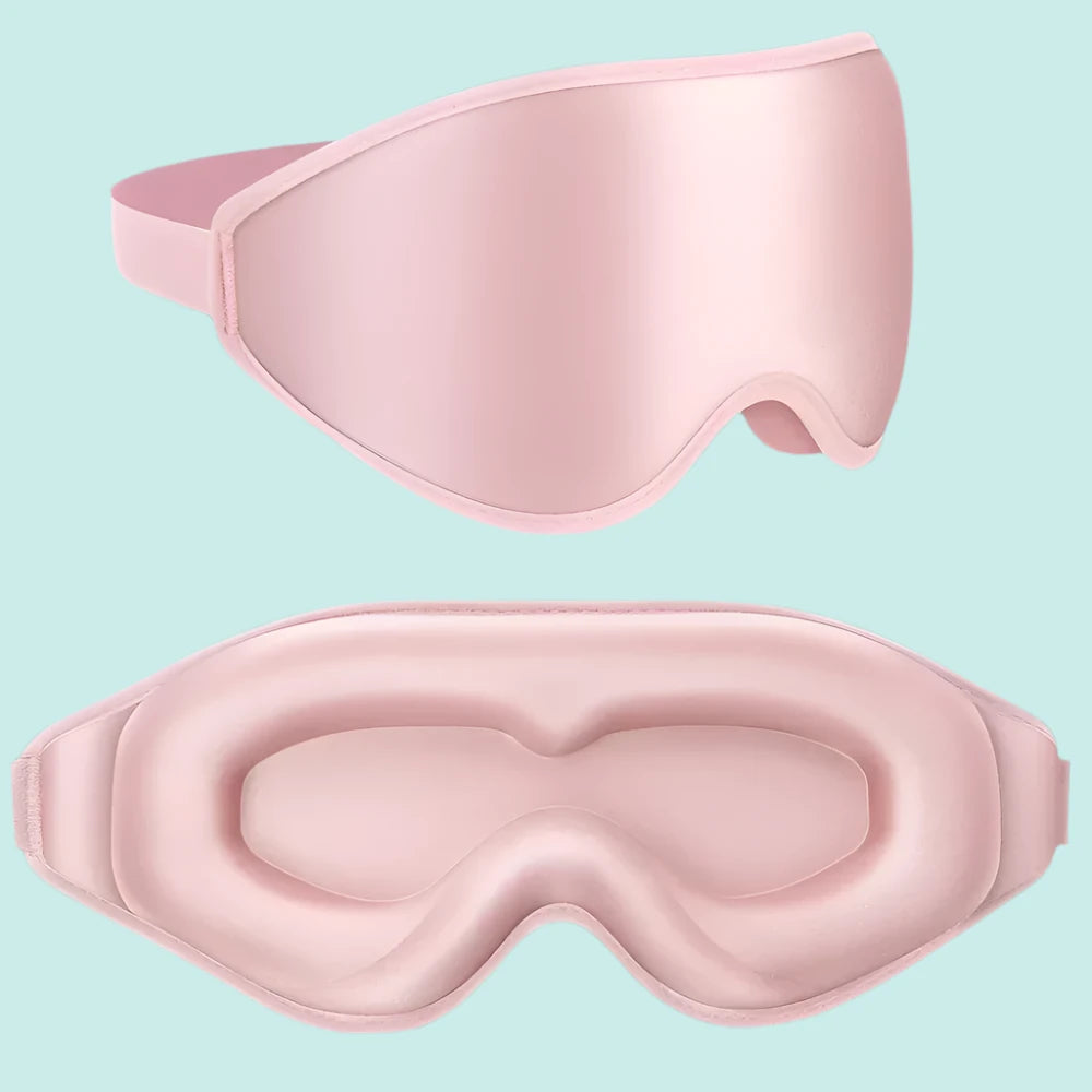 A soft blush pink 3D sleep mask gently placed on a plush pillow, designed for ultra-soft comfort and complete light blocking. Its contoured shape ensures zero pressure on the eyes, making it ideal for travel, naps, or cozy nights at home.