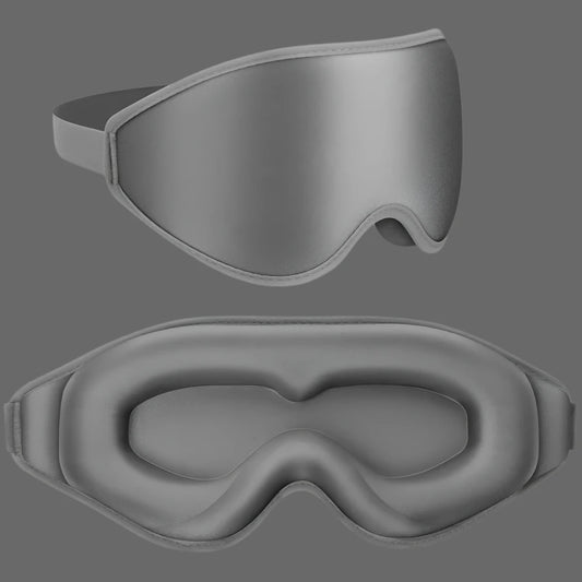 A cozy charcoal grey 3D sleep mask resting on a soft pillow, designed to provide ultra-soft comfort and 100% light blocking for a restful night's sleep. The mask's contoured shape ensures zero pressure on the eyes, making it perfect for travel, napping, or relaxing at home.