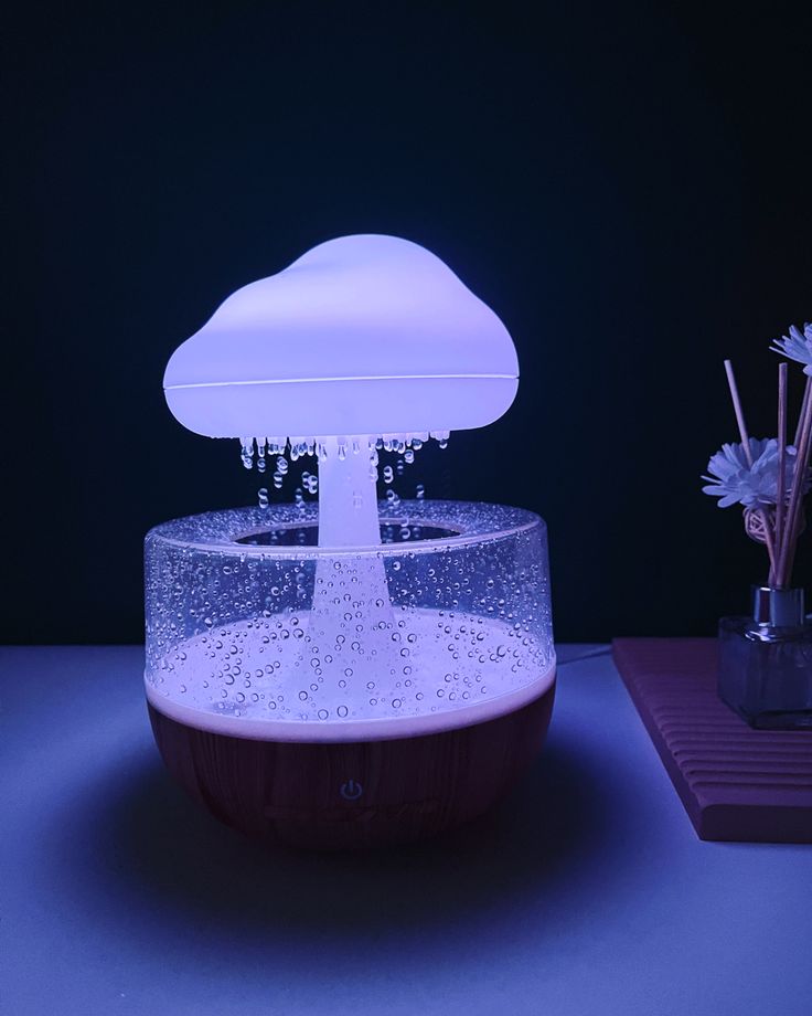 An innovative humidifier shaped like a cloud, emitting a soft mist that resembles raindrops. The device is illuminated with a soothing light, creating a tranquil environment ideal for relaxation and enhancing indoor air quality.